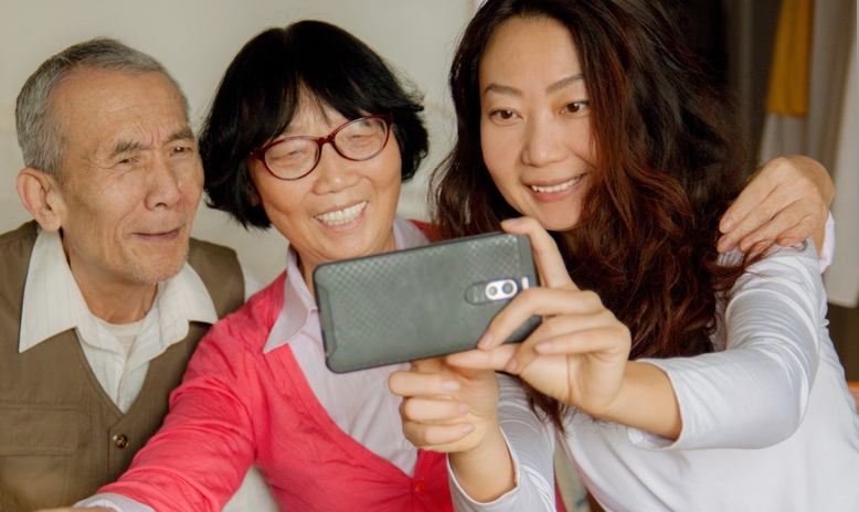 An elderly couple taking a selfie with their adult daughter